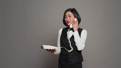 Asian-receptionist-answering-landline-phone-call-in-studio