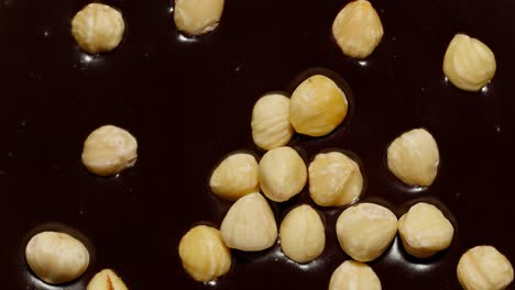 melted liquid dark chocolate and hazelnuts rotating close-up top view of molten liquid hot chocolate