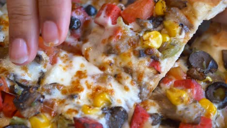 close-up of a slice of delicious pizza with corn, tomatoes, olives, mushrooms, and pepperoni