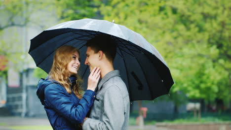 Stylisches-Junges-Paar,-Das-Sich-Unter-Einem-Regenschirm-Umarmt,-Es-Regnet-HD-Video
