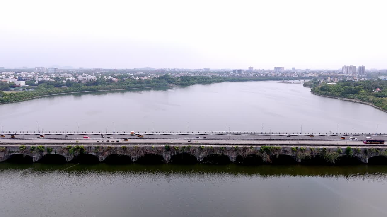 Busy 6 lane bridge over a river during daytime in India. Aerial view.