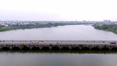 busy 6 lane bridge over a river during daytime in india. aerial view.