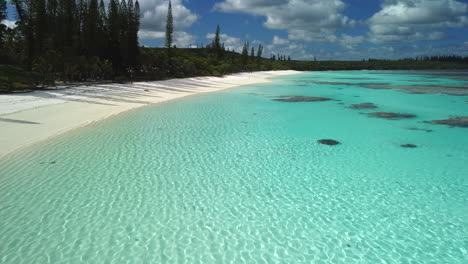 Low-flyover-above-beautiful-clear-water-and-white-sand-of-Yejele-Beach,-Maré-Island