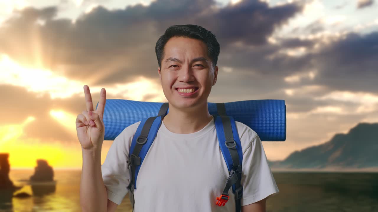 Close Up Pria Asia Pendaki Gunung Dengan Ransel Mendaki Tersenyum Dan Menunjukkan Gestur Damai di Pantai