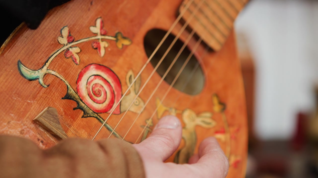 Mani che strimpellano una chitarra acustica decorata vicino alla buca, dita che si muovono con sfocatura ritmica mentre una calda luce interna evidenzia le venature del legno, la trama della manica, un'atmosfera di pratica concentrata, con chitarra acustica.