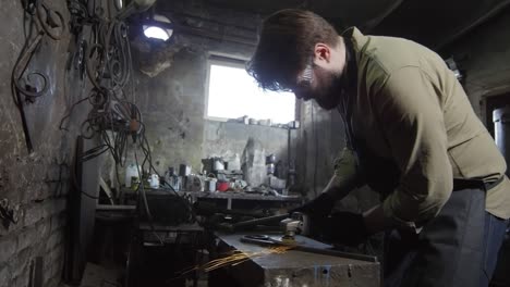 handsome caucasian blacksmith working in smithy