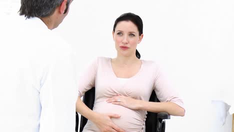 pregnant woman sitting on wheelchair talking with a doctor