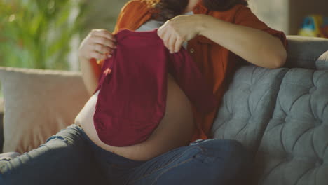 pregnant woman looking at baby clothes