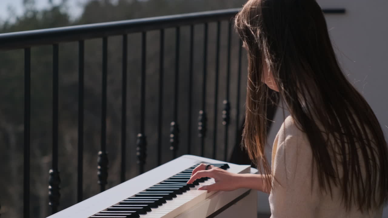 una chica joven tocando el piano en el balcón.