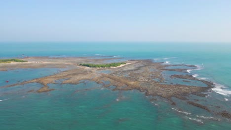 rocky island with tropical growth in the middle, surrounded by blue calm ocean