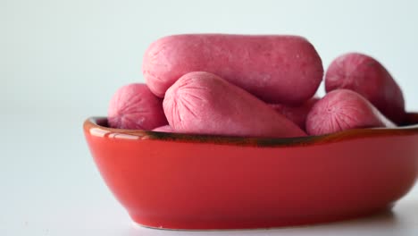 pink mini sausages in a red bowl