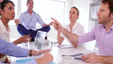 handsome businessman meditating while his colleagues are arguing