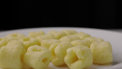 cerca de los bocadillos de comida crujiente anillos de maíz patatas saladas gira lentamente. comida rápida o comida chatarra bocadillos concepto no saludable.