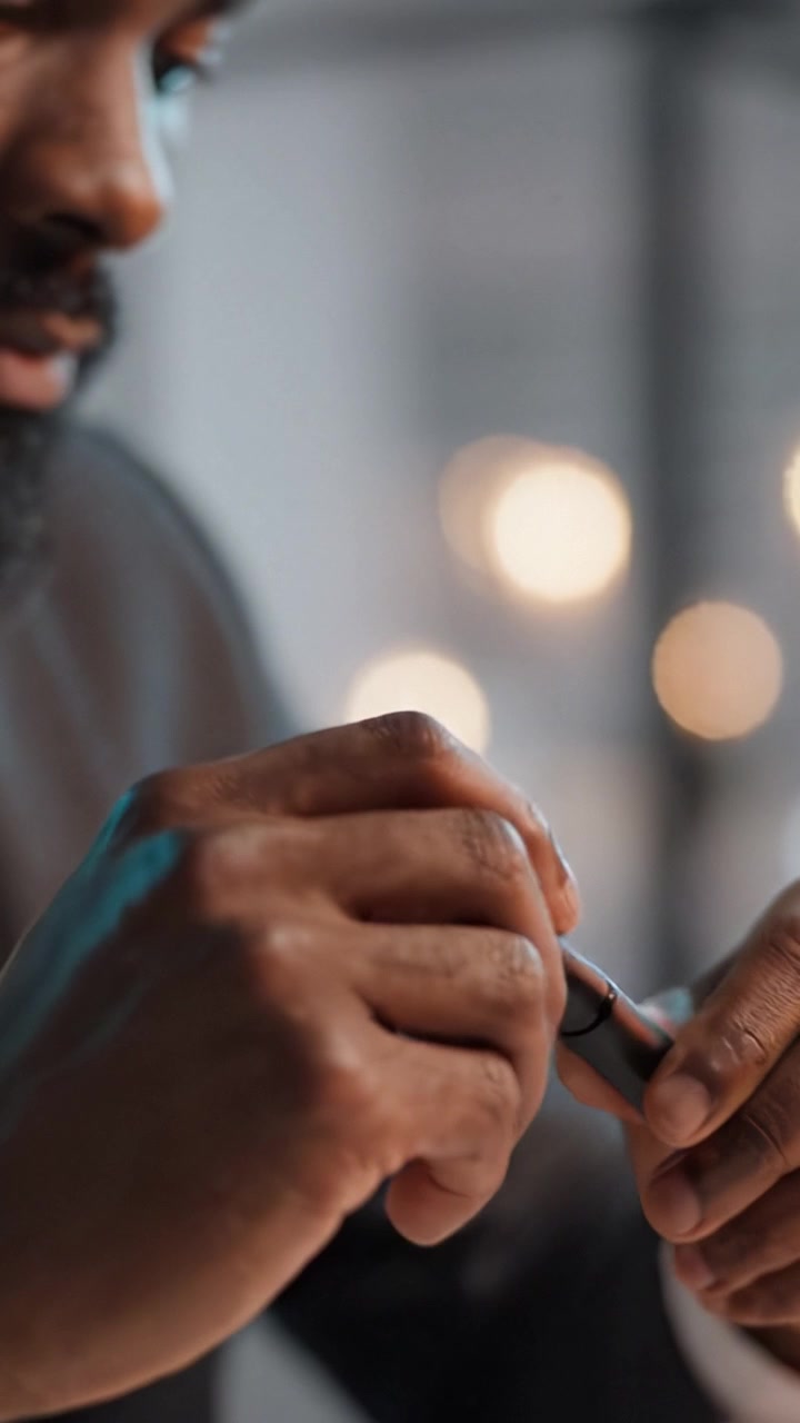 Una persona intenta a usare una penna e uno smartphone, che illustra le dinamiche della comunicazione moderna e del flusso di lavoro in un contesto elegante con luci sfocate sullo sfondo.