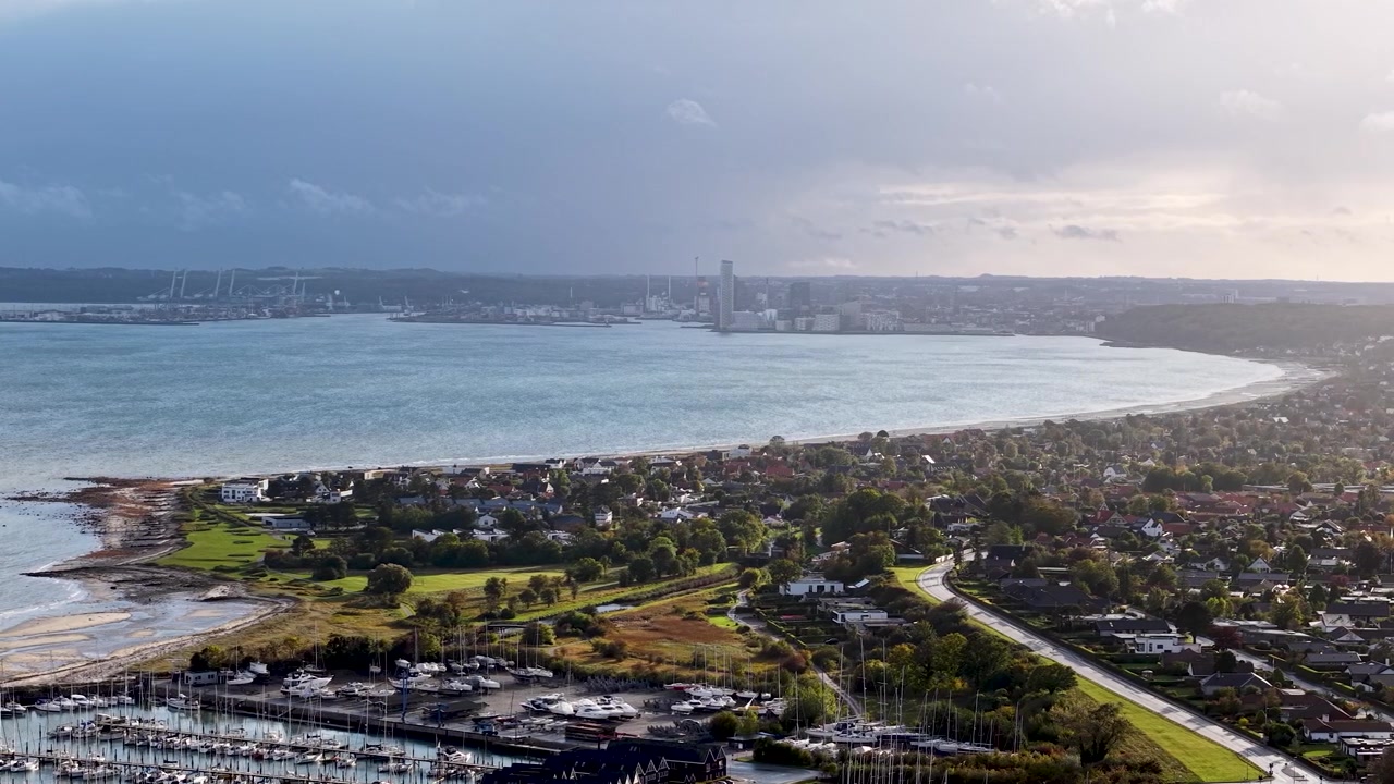 Luftaufnahme mit Drohne von der Aarhus Bucht und Egaa Marina, die sich entlang der malerischen dänischen Küste unter dramatischem Himmel erstreckt