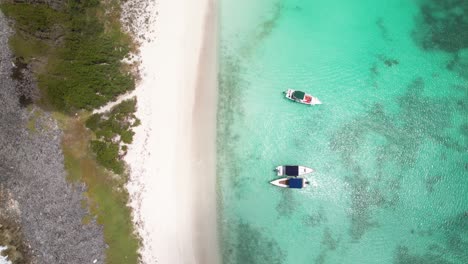 zenithal aerial view beach crasky island, tilt up reveal natural landscape and yachts