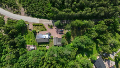 Birds-eye-drone-shot-of-a-detached-house-with-solar-panels-on-roof,-summer-day