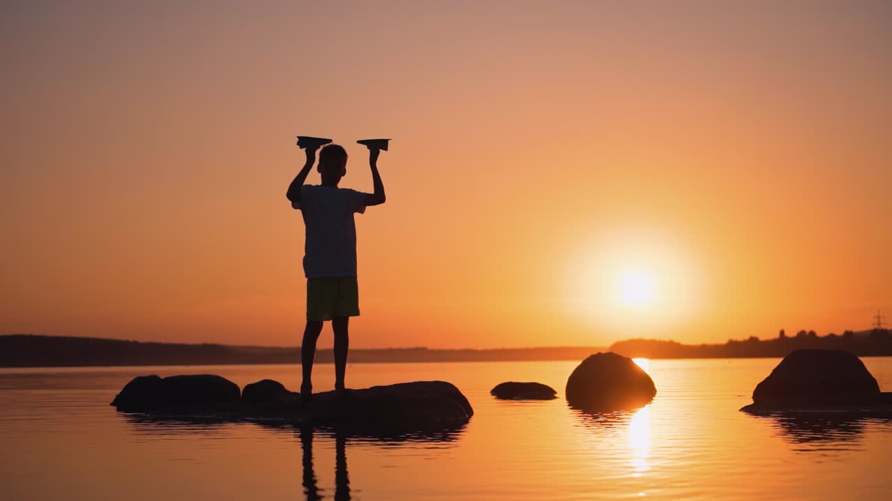 A happy child is playing with a paper airplane at sunset. Classes with children outdoors. Lifestyle