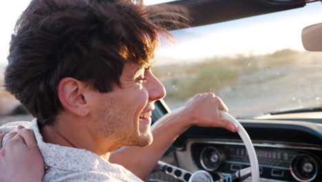 Young-white-couple-driving-open-top-car,-side-view,-close-up