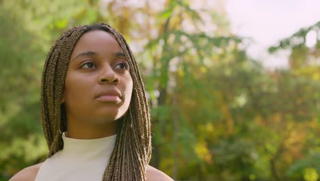 thoughtful young woman with braided hair in a park
