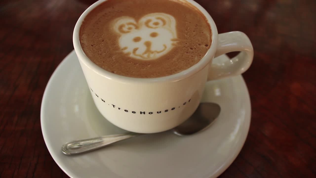 Primo piano di un caffè latte con 'latte art' a forma di orso posizionato su un tavolo di legno