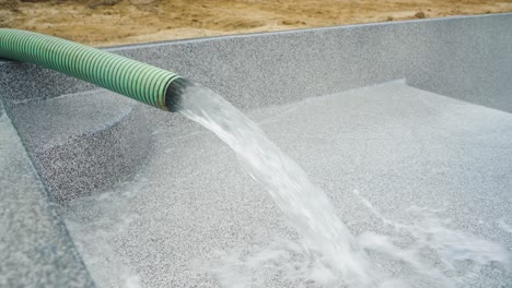water pours into backyard fiberglass pool during installation process