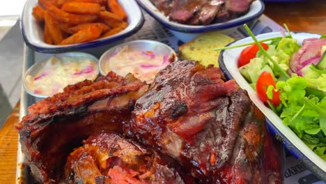 Costillas-De-Cerdo-Con-Ensalada,-Pechuga-De-Ternera-Con-Batatas-Fritas,-Pan-De-Maíz-Y-Ensalada-De-Col,-Comida-Tradicional-Americana,-Toma-De-4k