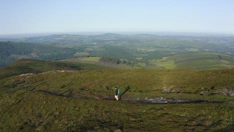 Aerial-view,-Woman-tourist-traveler-walking-on-the-top-of-mountain-in-summer-sunny-day-under-sun-light