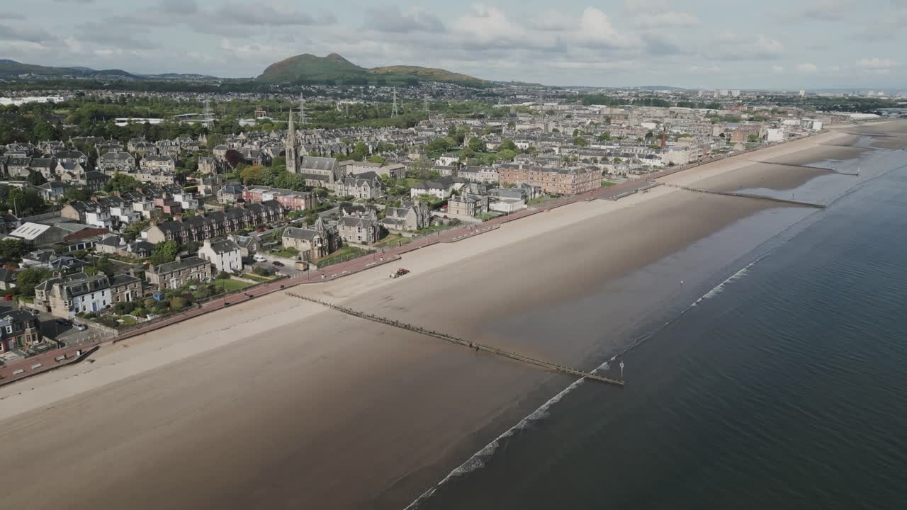 Kuststad i Edinburgh, Skottland, med strandpromenad och strand vid lågvatten med vågbrytare