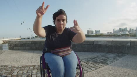 portrait of young woman dancing using wheelchair outdoors