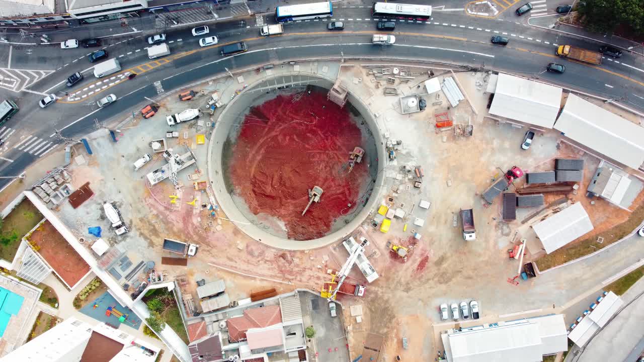 excavación del eje de lanzamiento para la construcción de la estación de metro que muestra bulldozer y automóviles alrededor