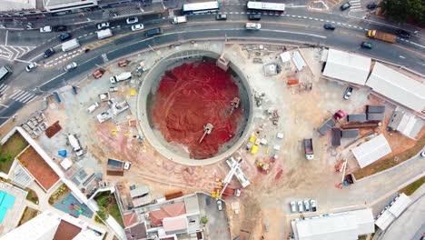 excavación del eje de lanzamiento para la construcción de la estación de metro que muestra bulldozer y automóviles alrededor