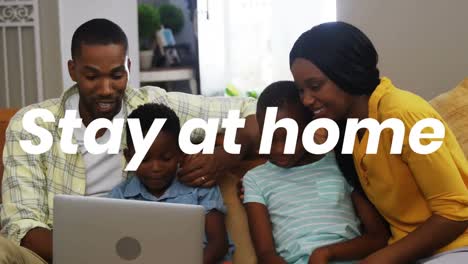 Animation-of-stay-at-home-text-over-parents-with-son-and-daughter-using-laptop-at-home