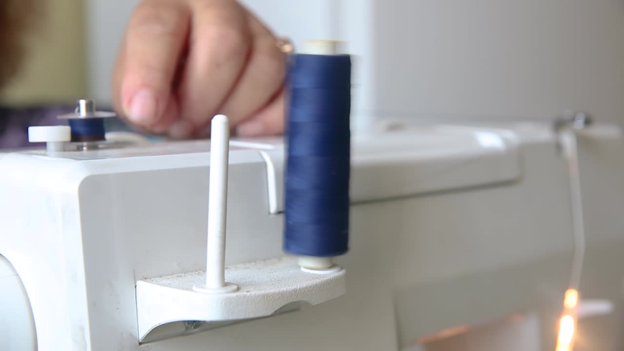 The seamstress winds a spool of thread on the sewing machine