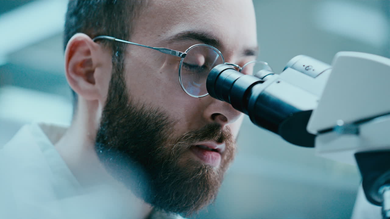 Researcher Using Microscope and Speaking with Assistant in Laboratory