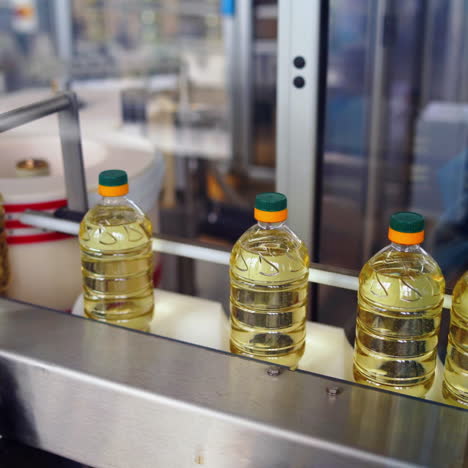 sunflower oil plant indoors. plastic bottles full of yellow oil moving on the conveyor line inside the modern factory background.