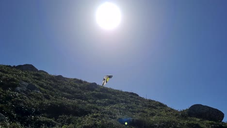 scene of person flying a paraglider near mountains with lots of vegetation and blue sky air sports on beach and cliffs