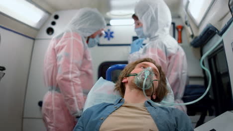 male patient in oxygen mask moving in emergency car to hospital