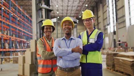 portrait of diverse workers wearing safety suits and smiling in warehouse