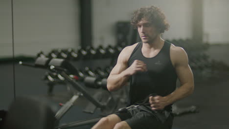muscular man working out on rowing machine at gym