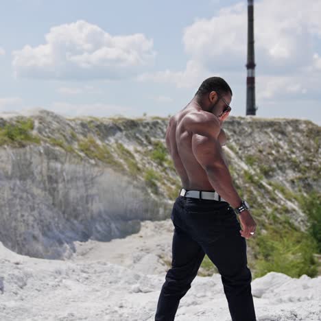 athletic african man without shirt walks on hill. muscular dark skinned sportsman among nature in summer. slow motion