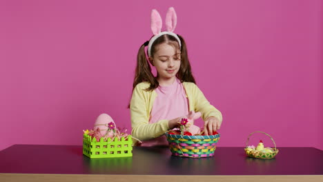 excited young girl arranging painted eggs in a basket to prepare for easter