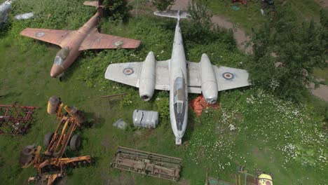 Aerial-orbit-over-the-remainings-of-the-former-Royal-Air-Force-jet-Gloster-Meteor-standing-in-the-field-in-Worcestershire,-UK