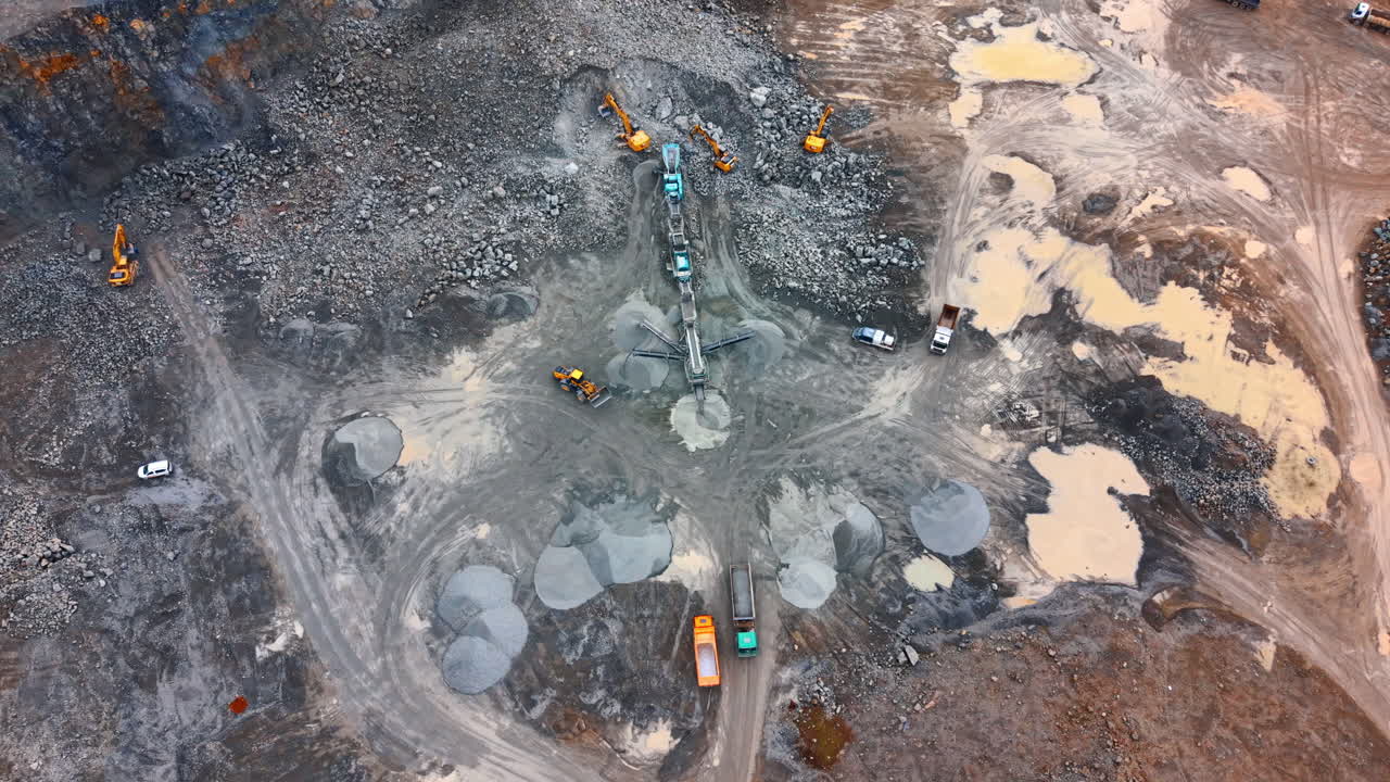 Aerial view of stone crushing plant and heavy machinery. Top down perspective of a mobile crushing facility surrounded by excavators and dump trucks