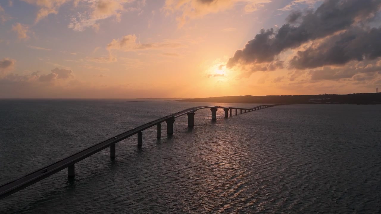 Inquadratura orizzontale con carrellata in avanti da un'angolazione obliqua elevata, sopra il Ponte dell'Isola di Irabu e l'oceano al tramonto a Miyako, Okinawa, Giappone