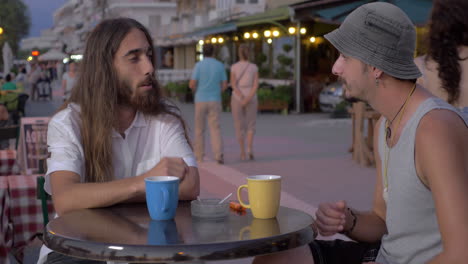 two men having talk and drinks in street cafe