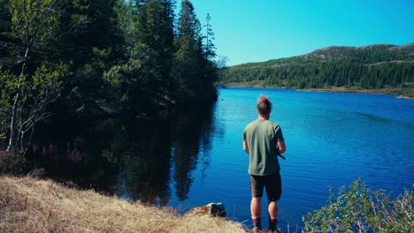 A-Man-Fishes-in-the-Serene-Waters-of-Seterdjupna-in-Indre-Fosen,-Trøndelag,-Norway---Static-Shot