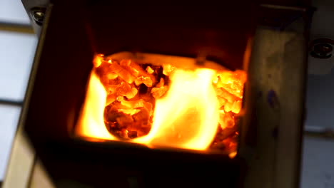 slow motion hand held shot of a yellow flame firing out he back of a table top pizza oven, flame coming out of a grill