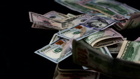 stack of united states dollar bills falling on scattering on black surface