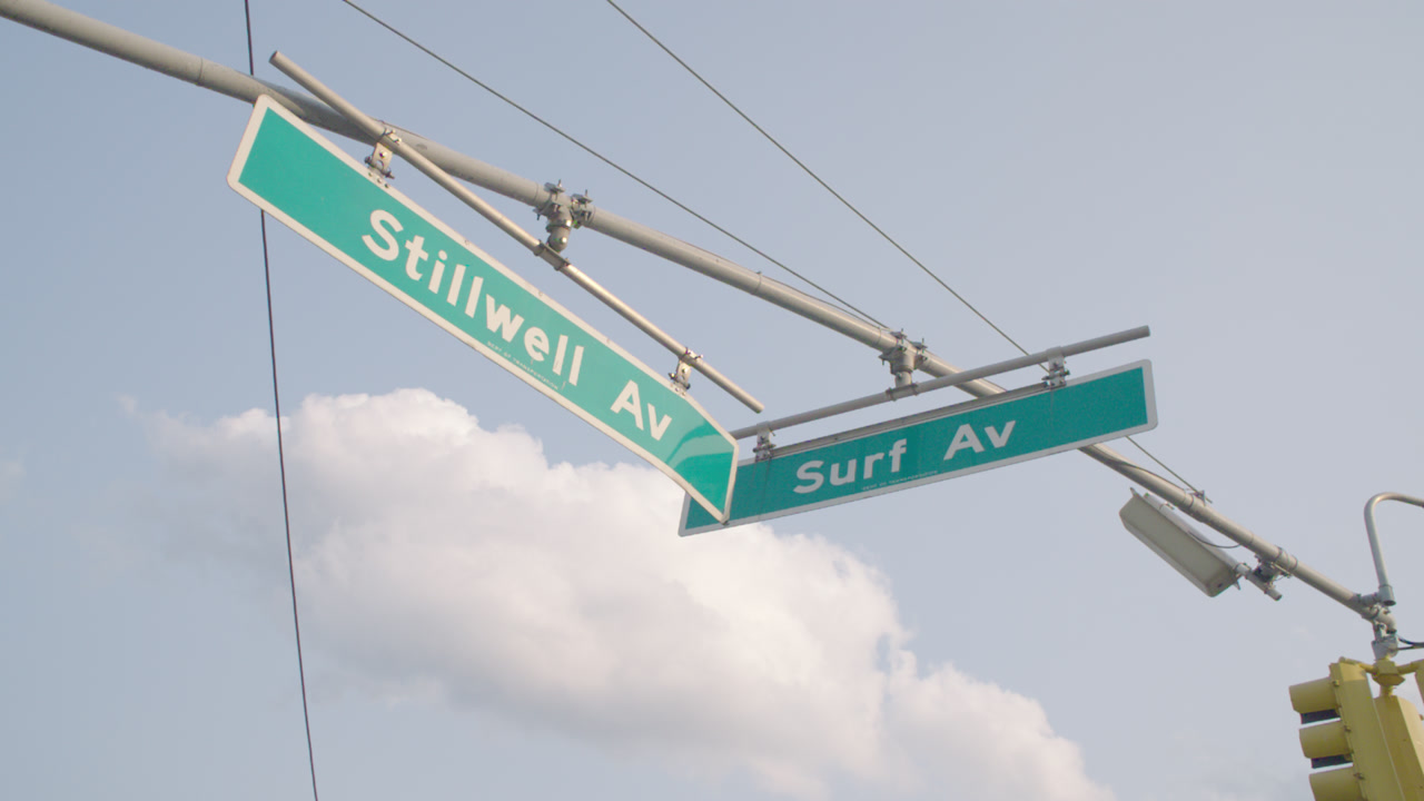 Establishing shot of street signs in Coney Island. Shot at the intersection of Stillwell Avenue and Surf Avenue in Brooklyn.